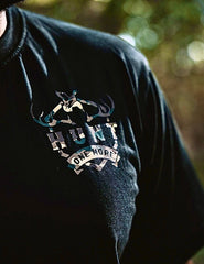 Close-up of the Hunt One More logo on the black Stripes and Antlers Camo tee