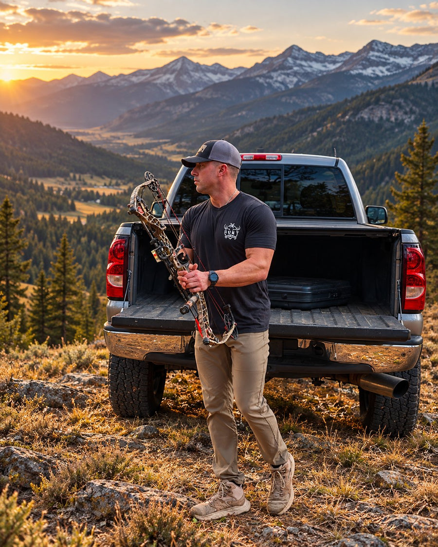Hunt One More founder Brad Gratton with his bow at the tailgate of his truck at a mountain sunset