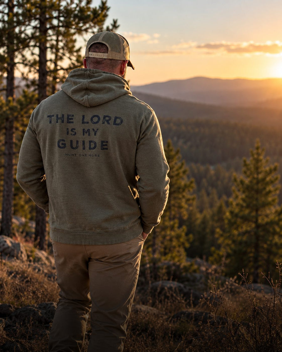 Hunter in The Lord Is My Guide hoodie overlooking a forest at sunset - Hunt One More hoodies