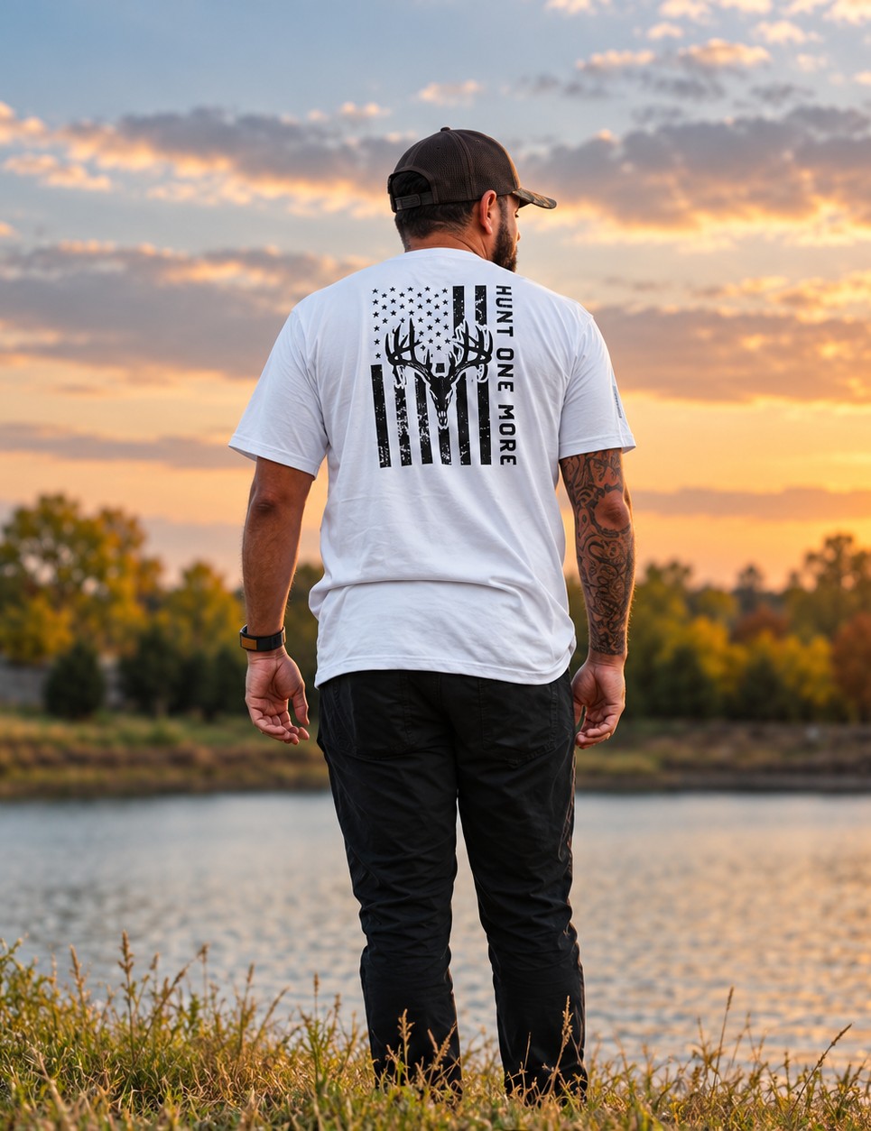 Man wearing the white Stripes and Antlers tee, distressed American flag and buck skull back print, at a lake at sunset – Hunt One More
