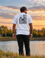 Man wearing the white Stripes and Antlers tee, distressed American flag and buck skull back print, at a lake at sunset – Hunt One More